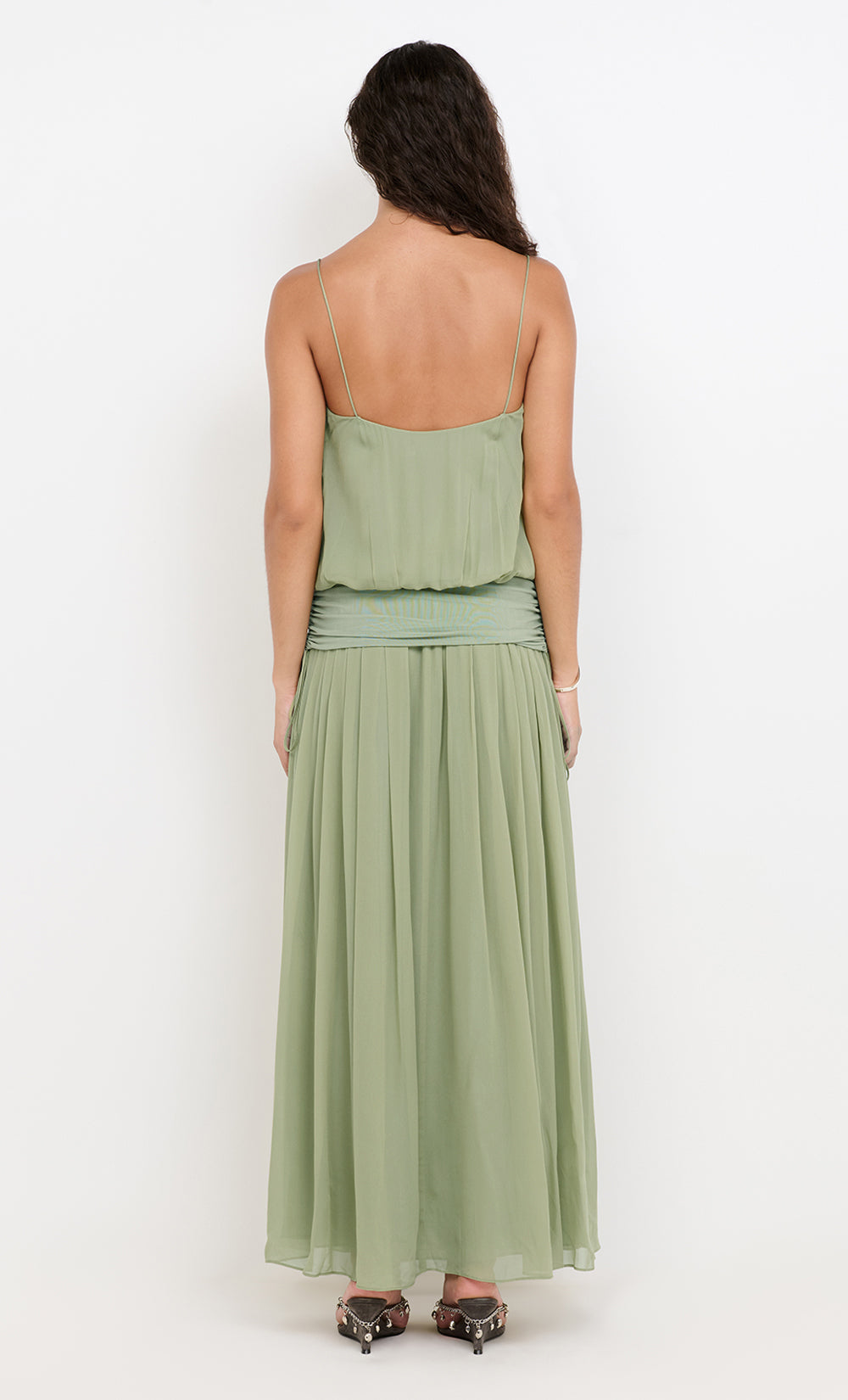 Woman wearing a green strapless dress with a plain white background