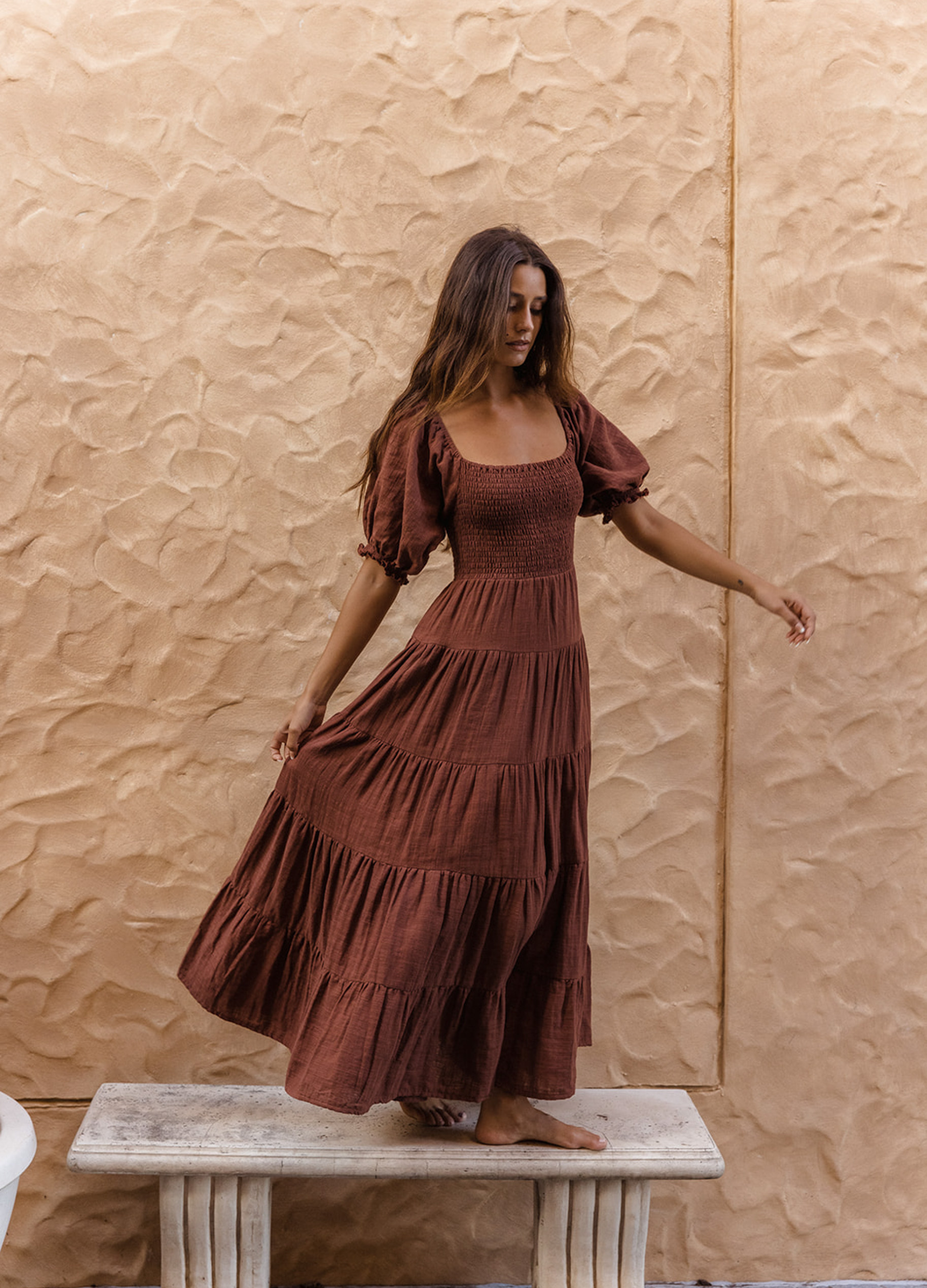 Model wearing chocolate brown tiered dress with short puffy sleeves