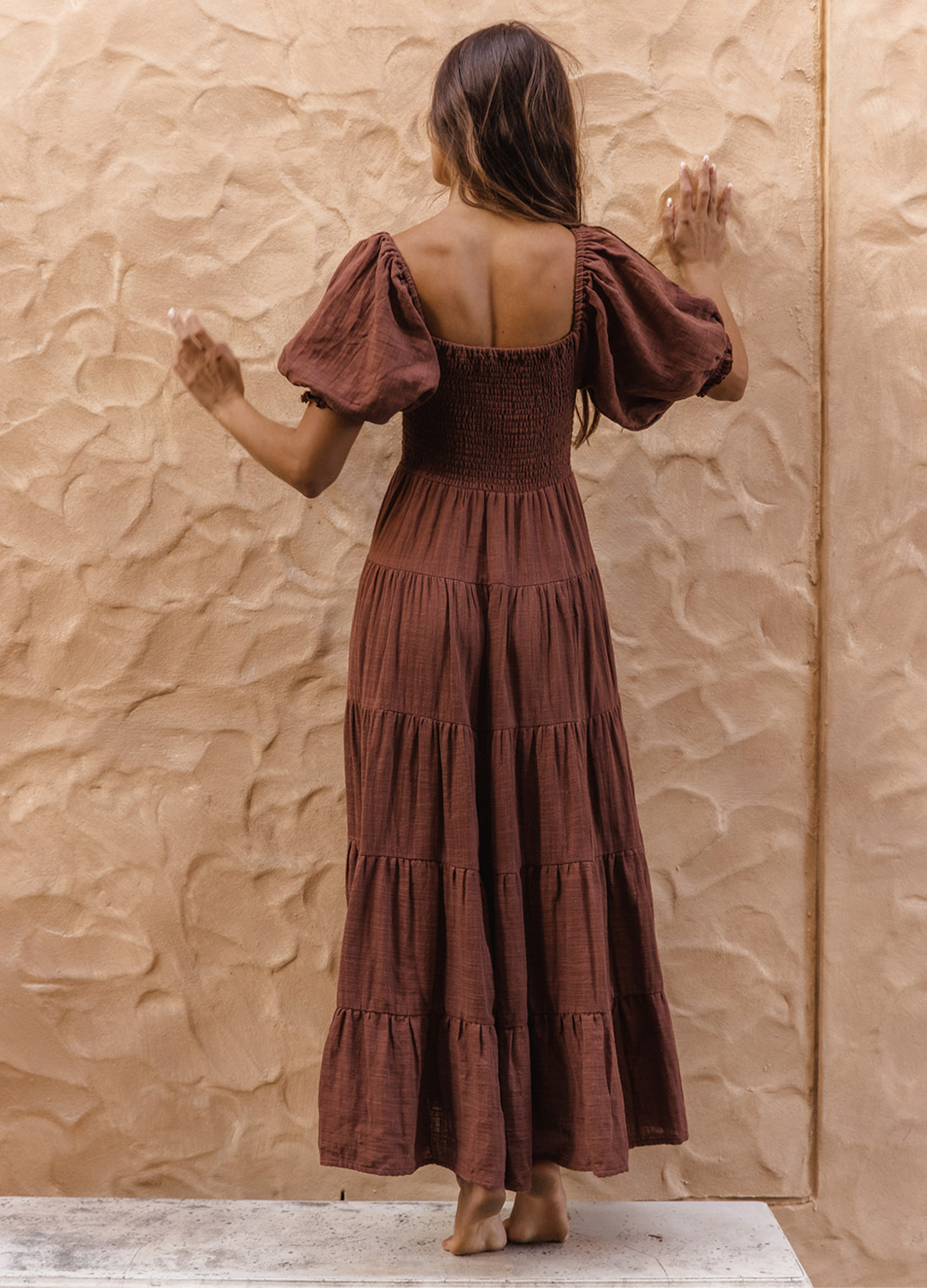 Model wearing chocolate brown tiered dress with short puffy sleeves