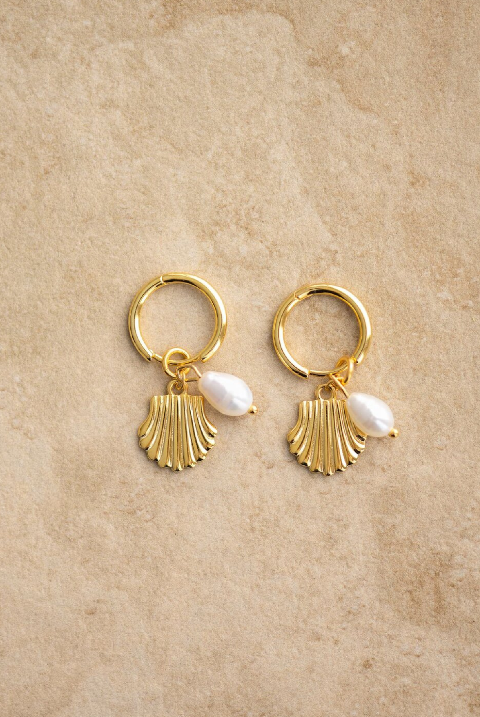 The Isla earrings have a gold shell design and a freshwater pearl