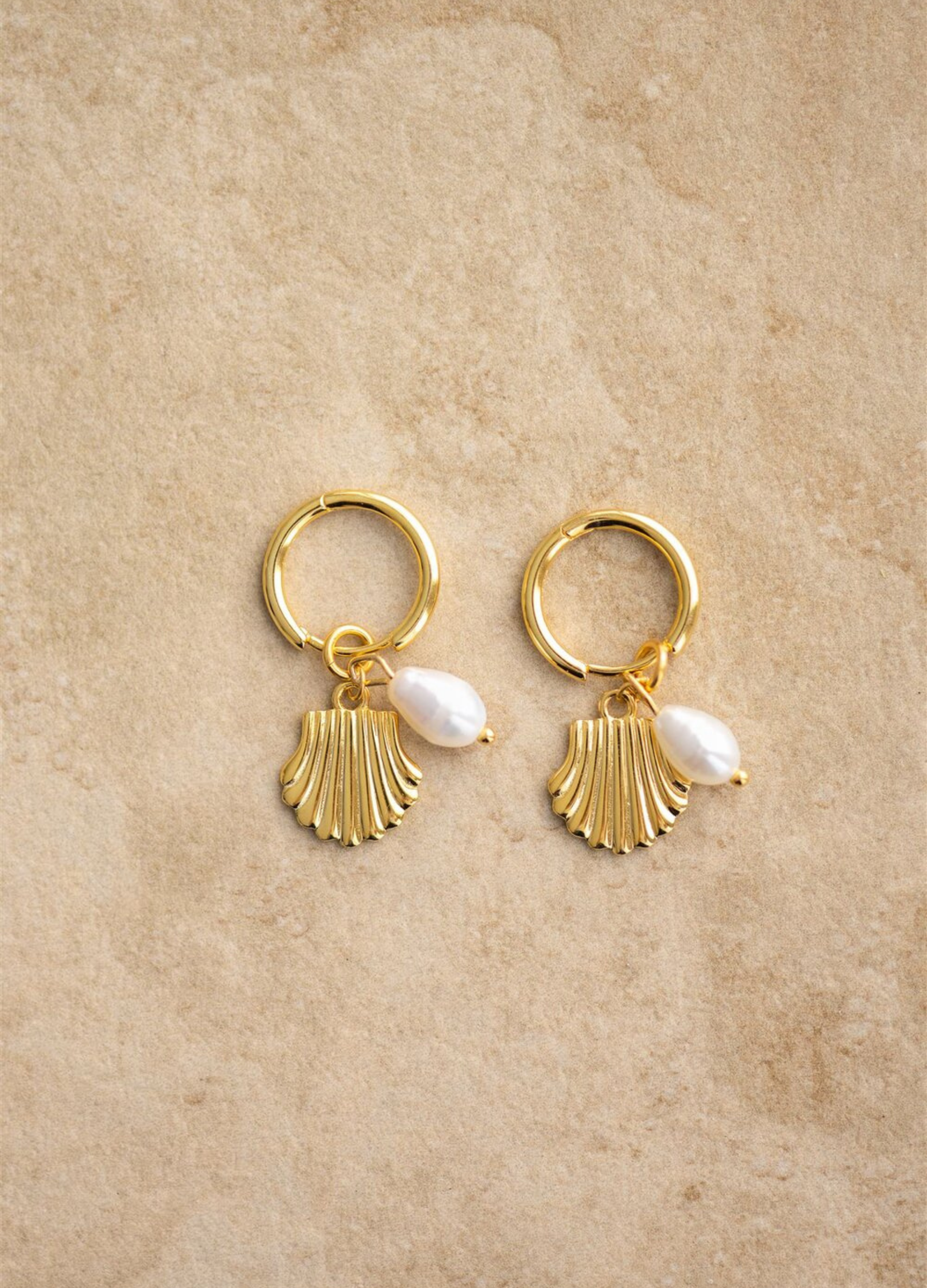 The Isla earrings have a gold shell design and a freshwater pearl