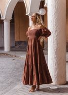 Model wearing chocolate brown tiered dress with short puffy sleeves