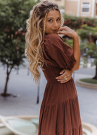 Model wearing chocolate brown tiered dress with short puffy sleeves