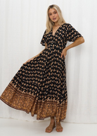 Model wearing the Iris Maxi Gypset Dress in black print with button front and cap sleeve