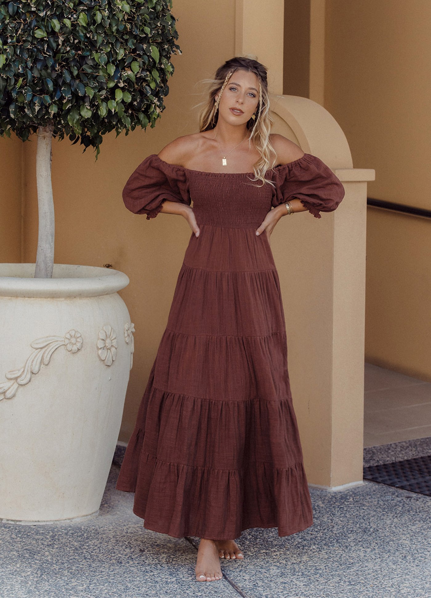 Model wearing chocolate brown tiered dress with short puffy sleeves