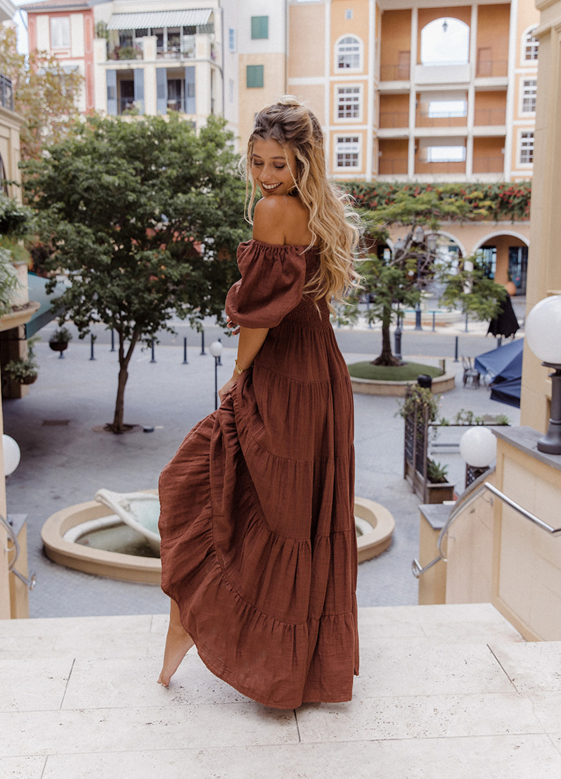 Model wearing chocolate brown tiered dress with short puffy sleeves