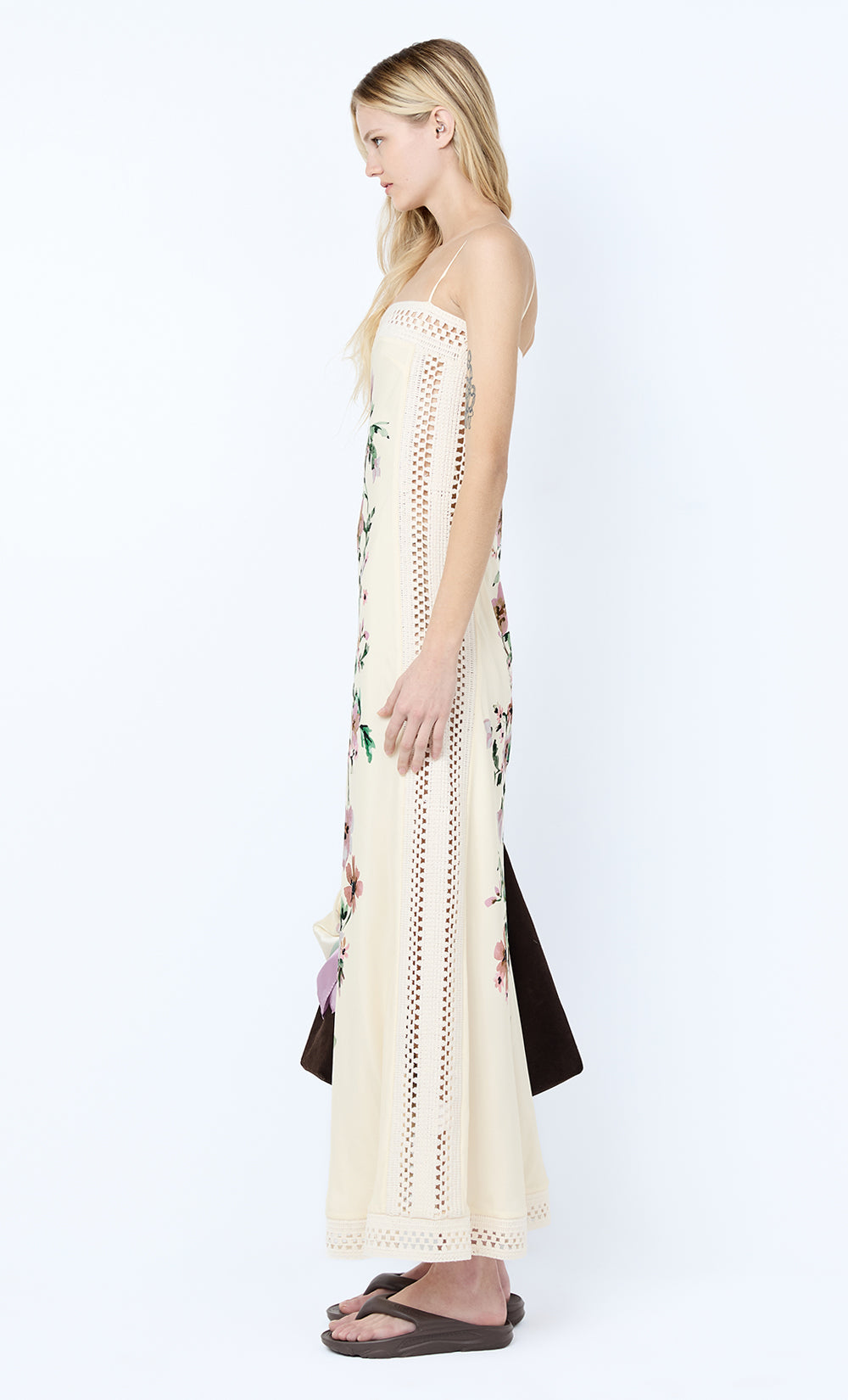 Woman wearing a long, light-colored dress with floral patterns on a white background