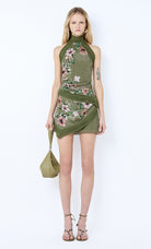 Woman wearing a green dress with floral embroidery on a white background