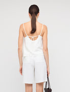 Woman wearing a white dress with thin straps on a plain background