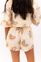 Person wearing a beige outfit with sun and moon pattern on a plain background