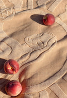 Three peaches on a textured beige surface with a detailed pattern