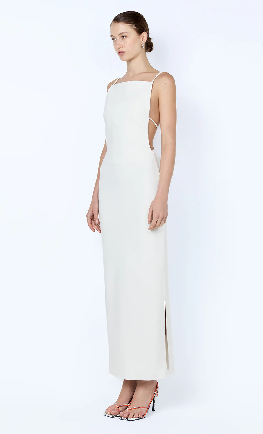 Woman wearing a white one-shoulder dress with cut-out details on a white background
