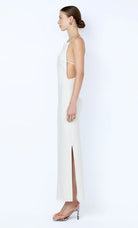 Woman wearing a white dress with thin straps and a slit on a white background