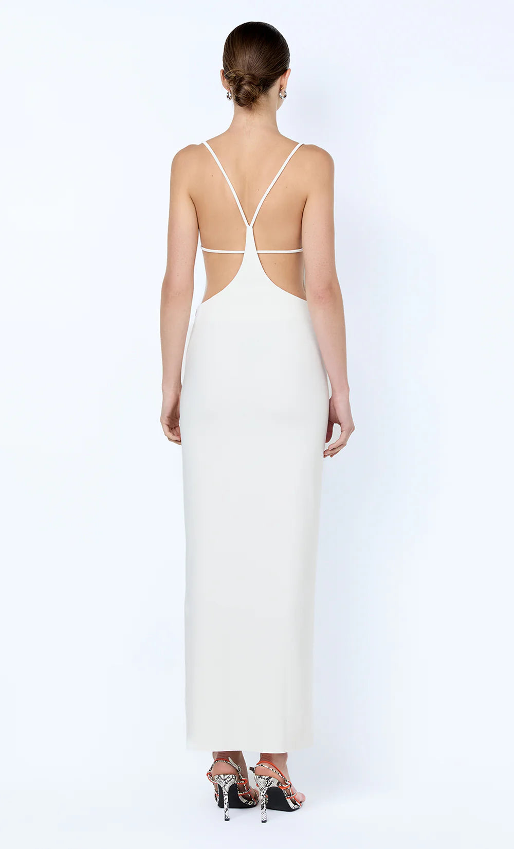 Woman wearing a white evening gown with a low back design on a white background