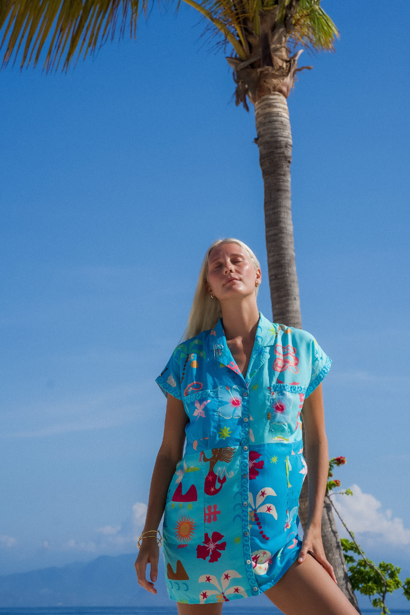 Woman wearing a colorful dress with a palm tree and blue sky in the background