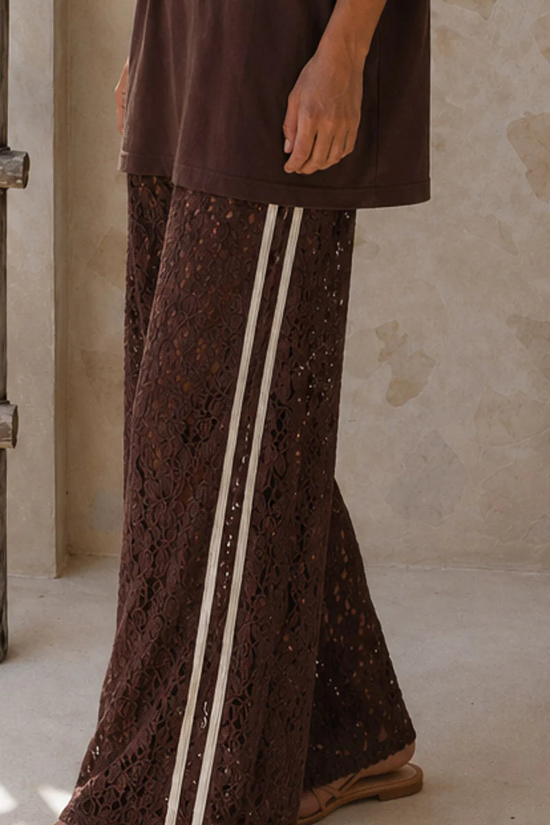 Brown lace pants with white stripes worn by a person against a neutral background
