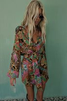 Woman wearing a colorful patterned dress against a teal wall