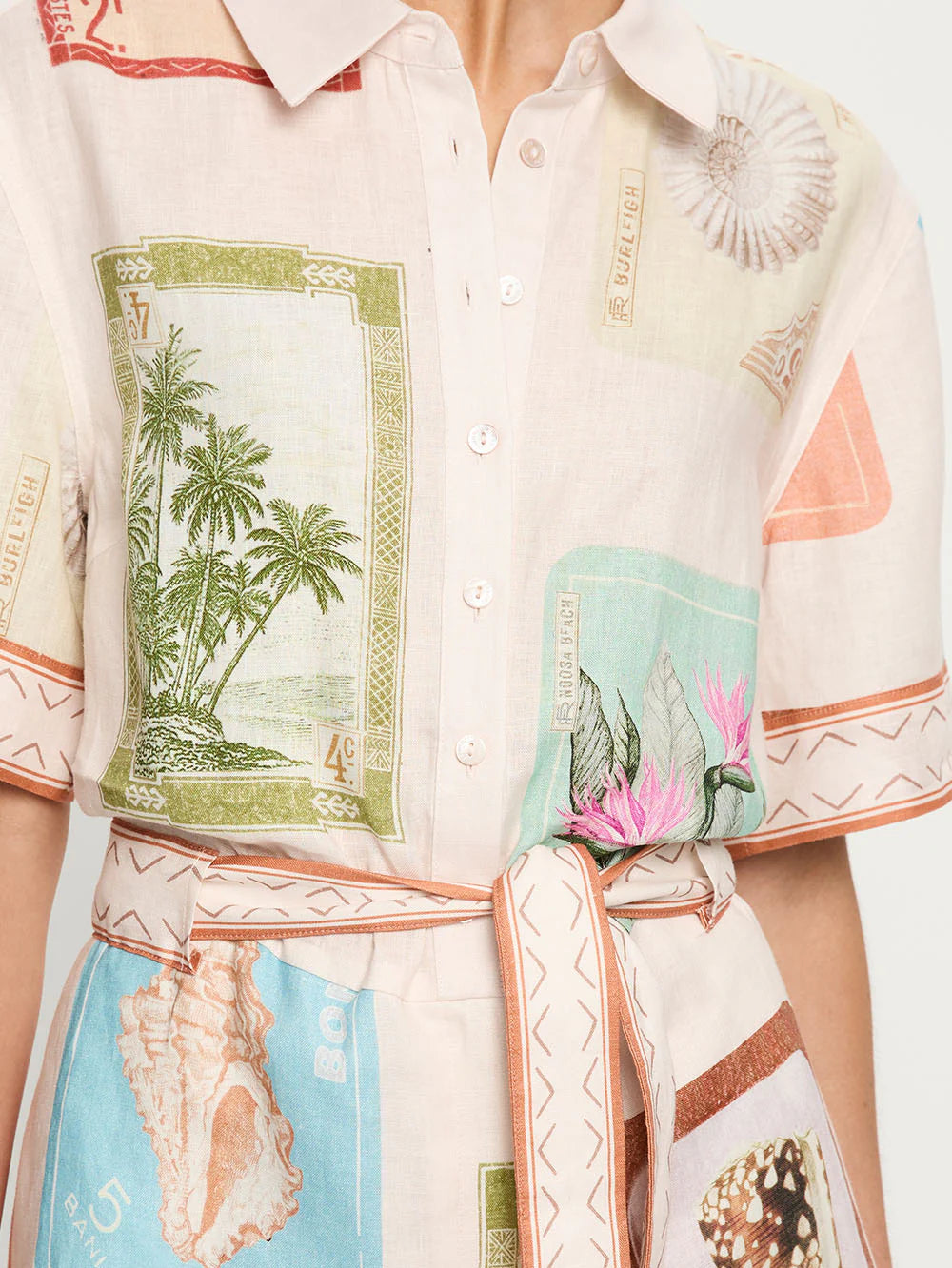 Close-up of a shirt with tropical-themed design featuring palm trees and shells.