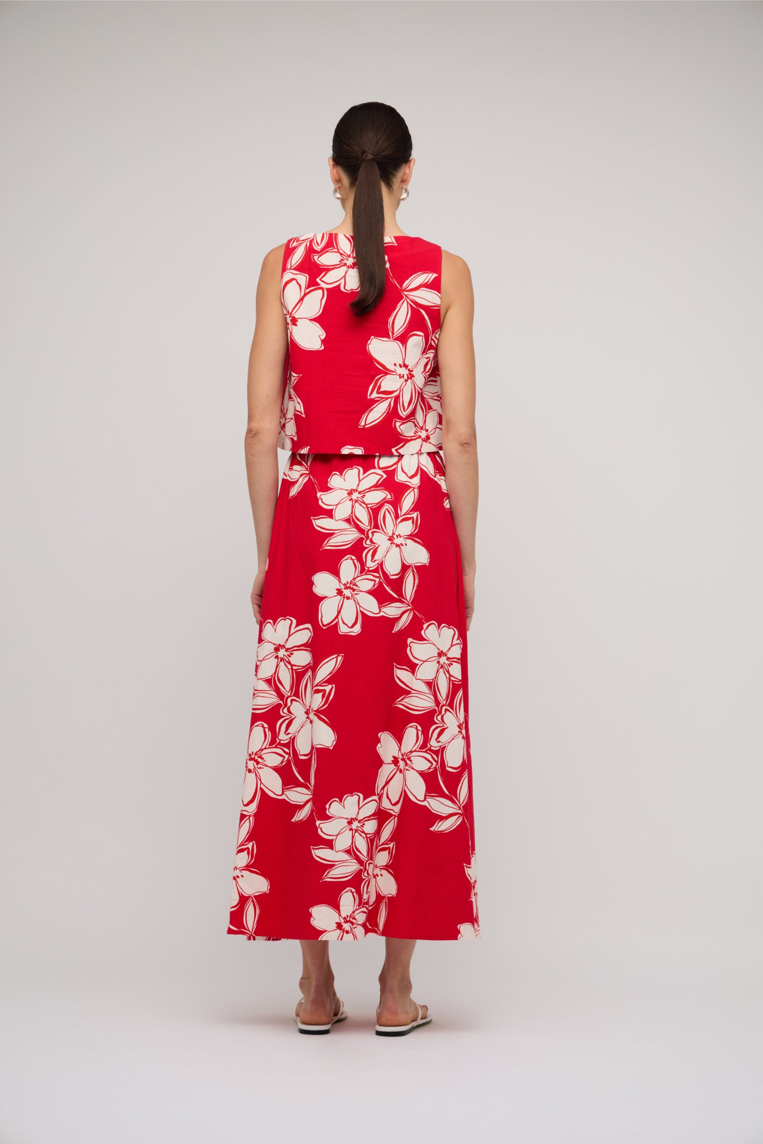 Woman wearing a red floral dress on a plain background