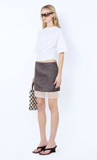 Woman wearing a white top and gray skirt with sunglasses on a white background Ema Asym Tee - Ivory