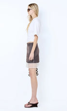 Woman wearing a white top and gray skirt on a white background