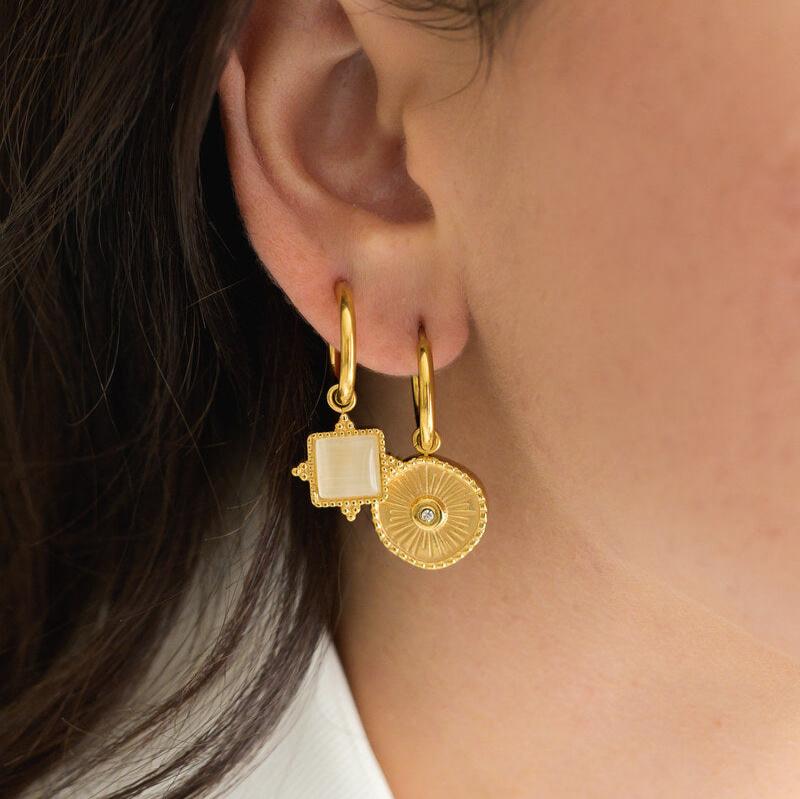 Gold earrings worn by a person with dark hair.