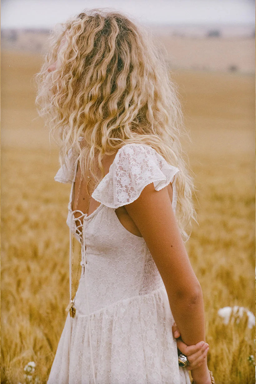 Woman in a white dress standing in a field of tall grass