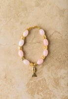 Bracelet with pink beads and gold accents on a beige marble background