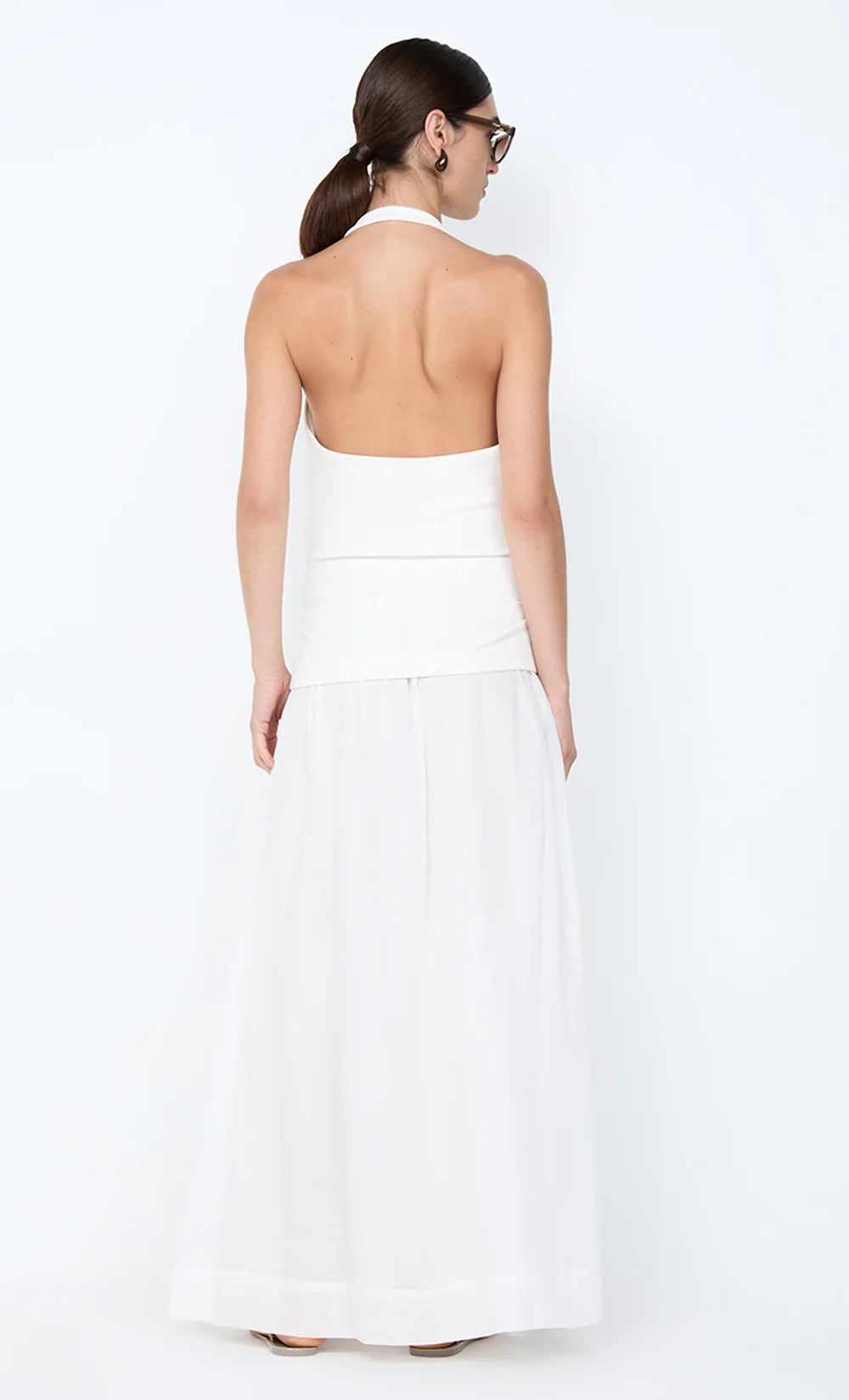 Woman wearing a white strapless dress against a white background