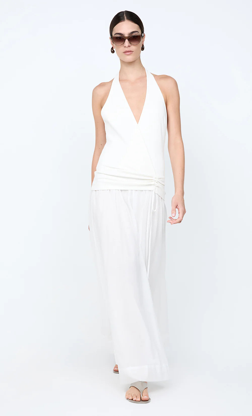 Woman wearing a white halter neck dress on a white background