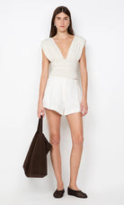 Woman wearing a white dress holding a brown bag on a white background