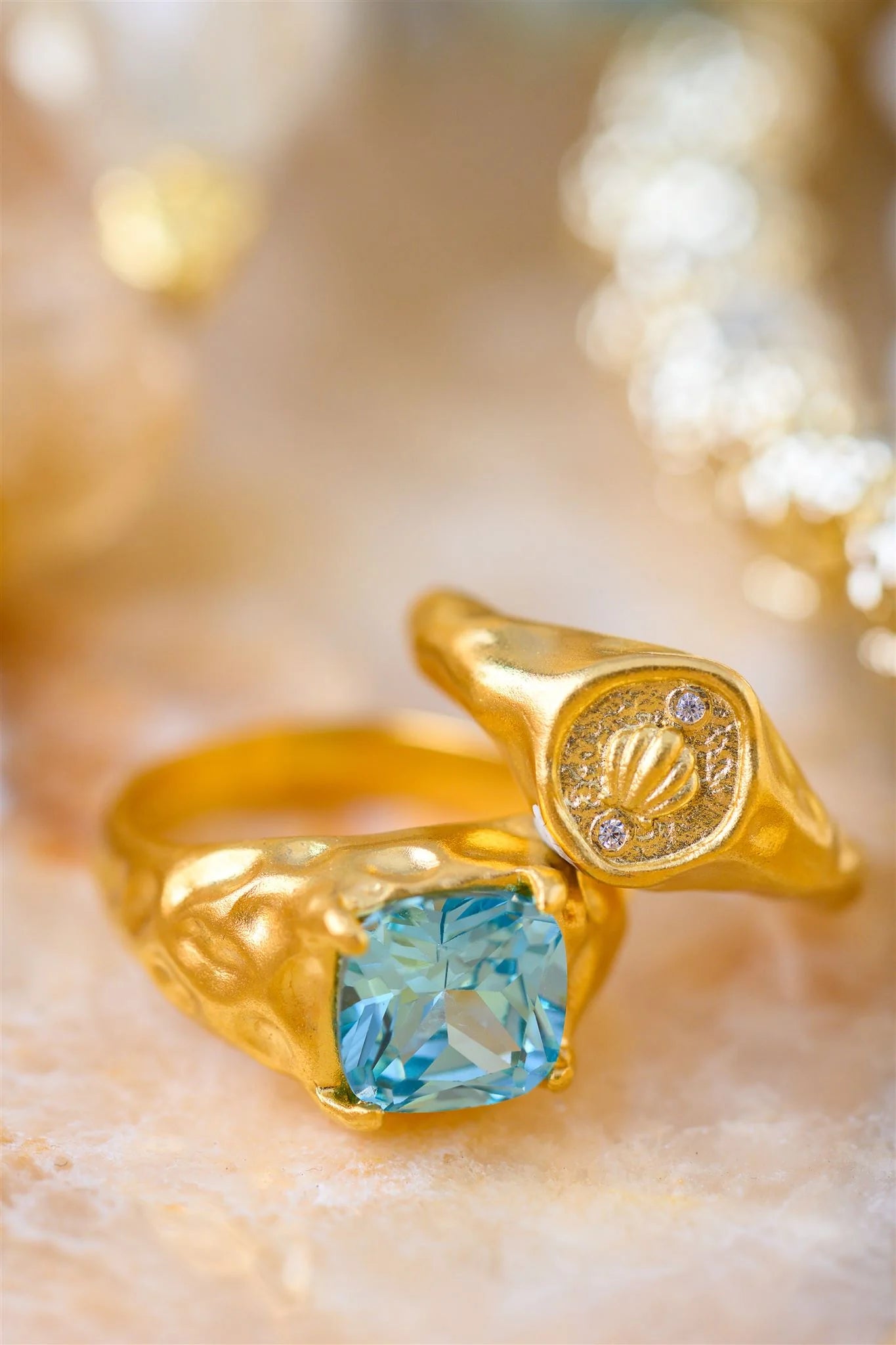 Gold ring with a blue gemstone on a blurred gold background