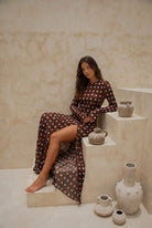 Woman in a polka dot dress sitting on stone steps with ceramic vases.