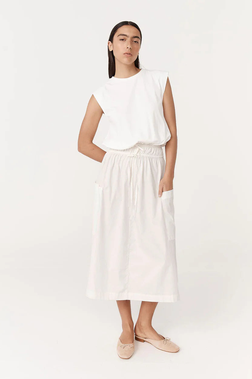 Woman wearing a white sleeveless top and white pants on a white background