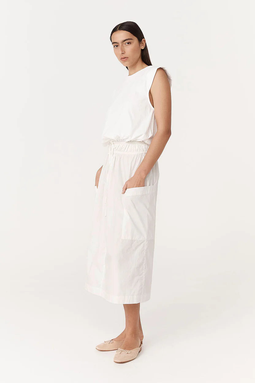 Woman wearing a white sleeveless top and pants on a white background