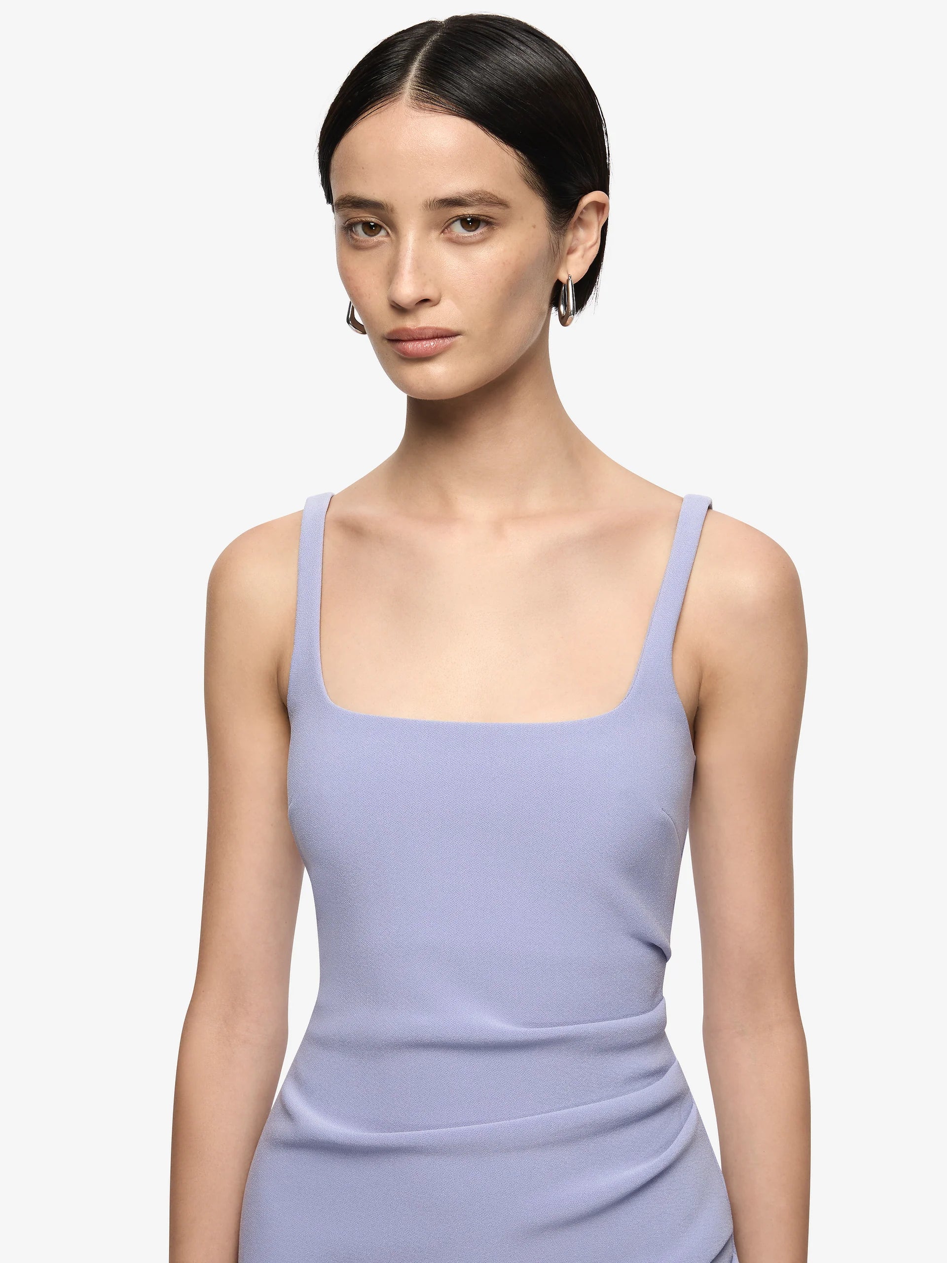 Woman wearing a light purple sleeveless dress against a plain background