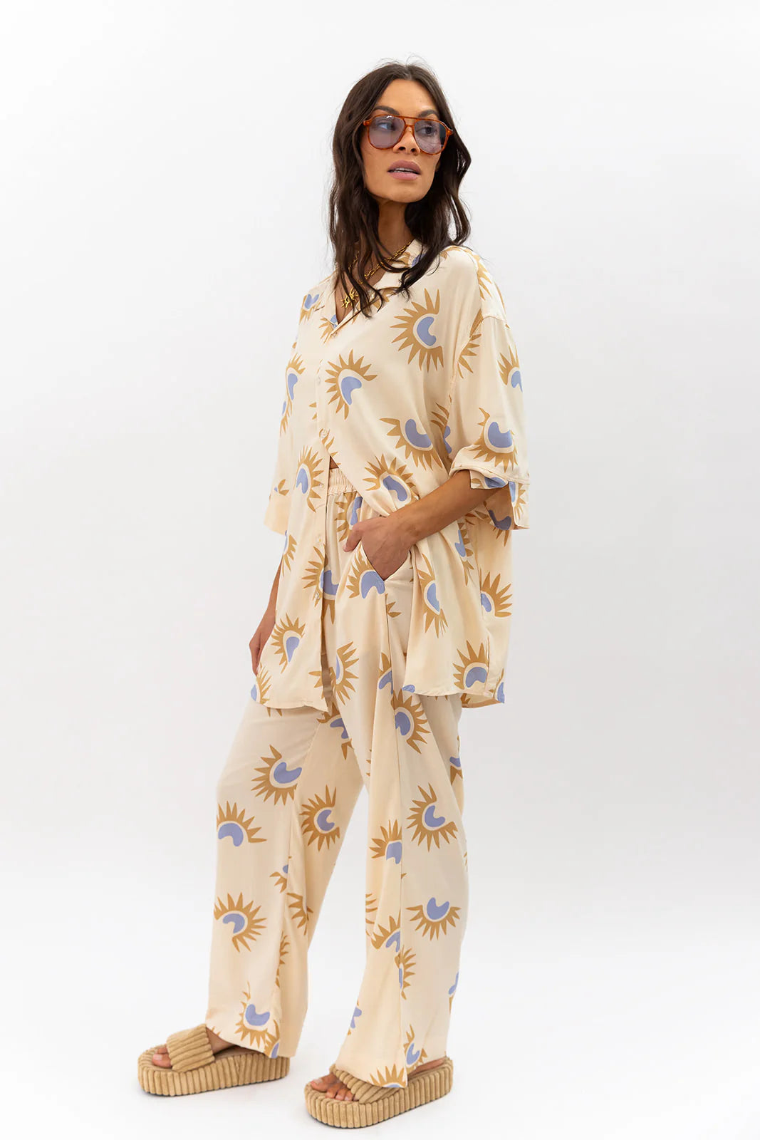 Woman wearing a beige pajama set with sun and moon pattern on a white background