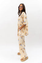 Woman wearing a neutral patterned outfit on a white background