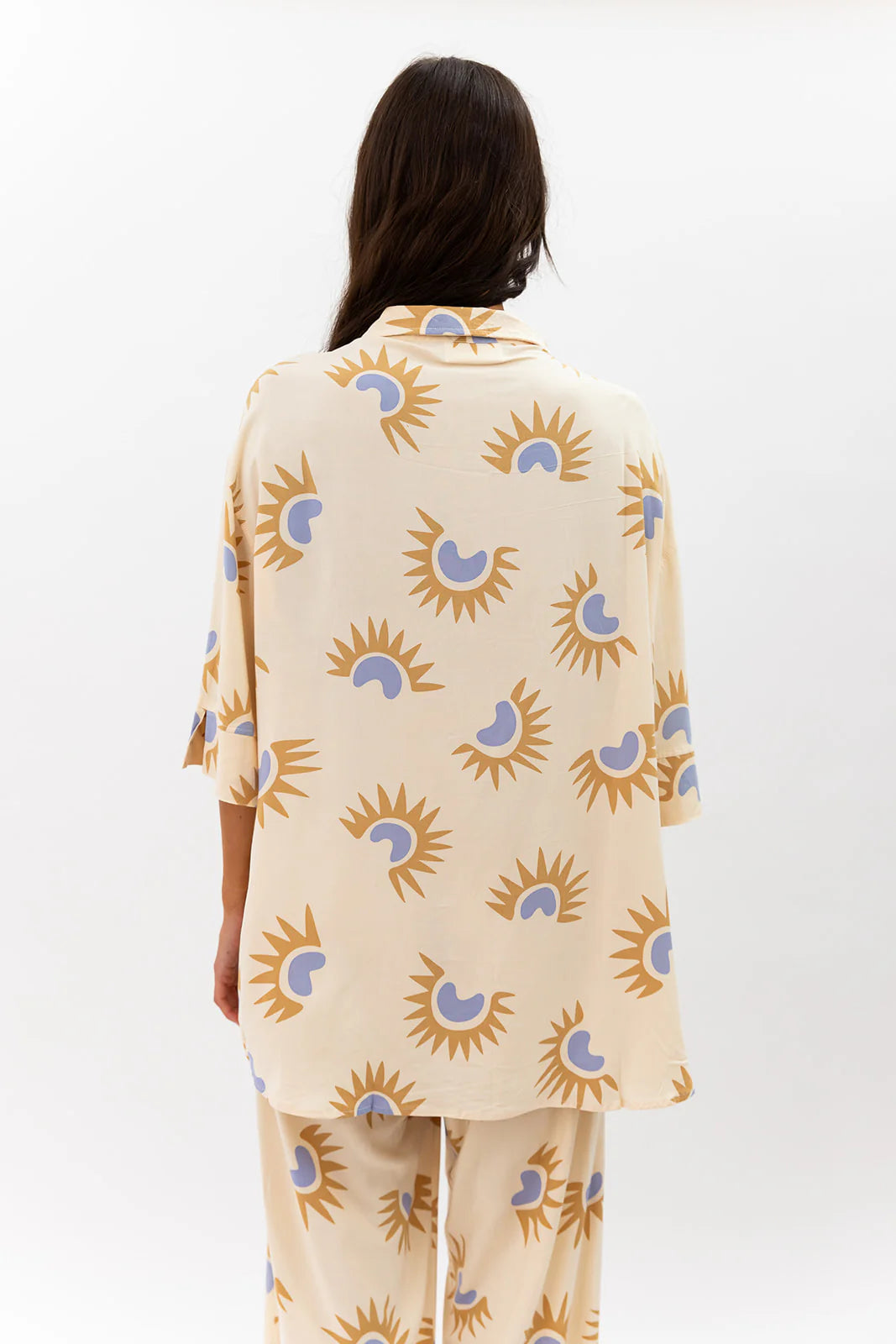 Person wearing a beige outfit with sun and moon pattern on a white background
