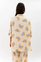 Person wearing a beige outfit with sun and moon pattern on a white background