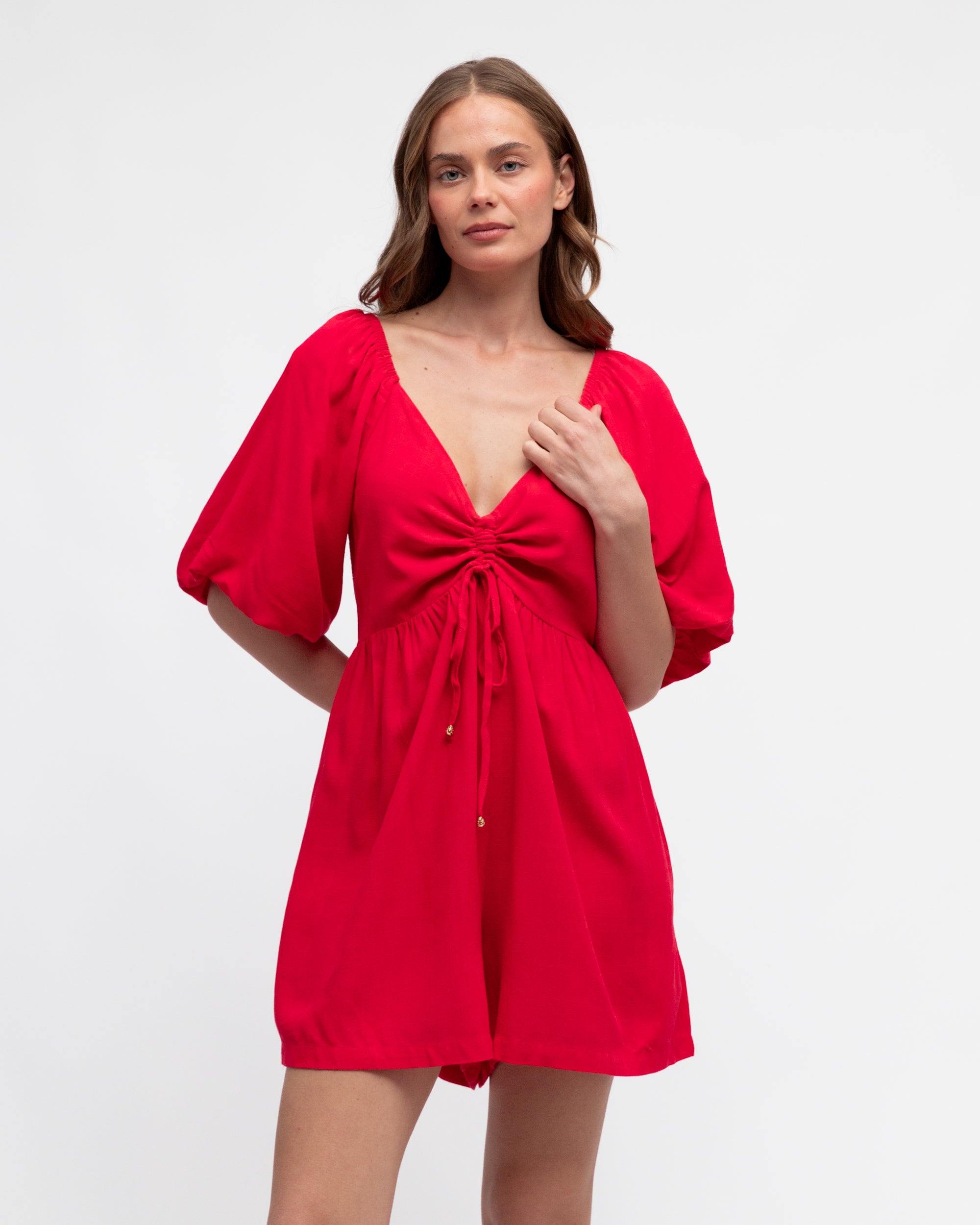 Woman wearing a red dress with puff sleeves on a white background