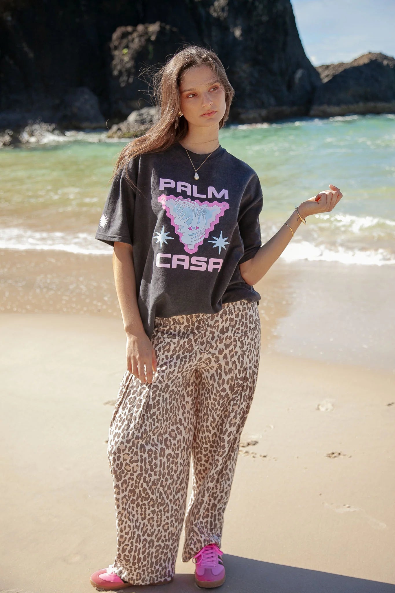 Person wearing a graphic t-shirt and leopard print pants on a beach