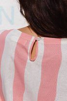 Close-up of a pink and white striped shirt with a button detail.