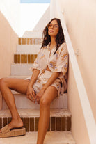 Woman in a patterned outfit sitting on steps outdoors