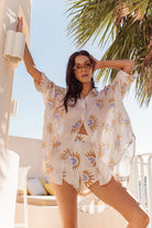 Woman wearing a patterned outfit with palm trees in the background