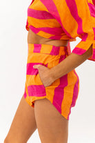 Person wearing a bright pink and orange striped outfit on a white background