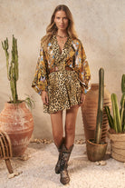 Woman in a leopard print outfit standing in front of cacti
