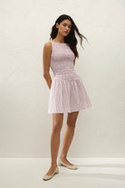 Woman wearing a pink and white striped dress against a plain background