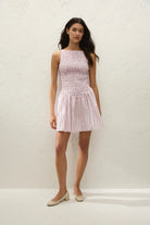 Woman wearing a pink pleated dress against a white background