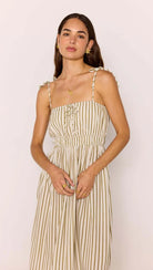 Woman wearing a beige and white striped dress against a plain background